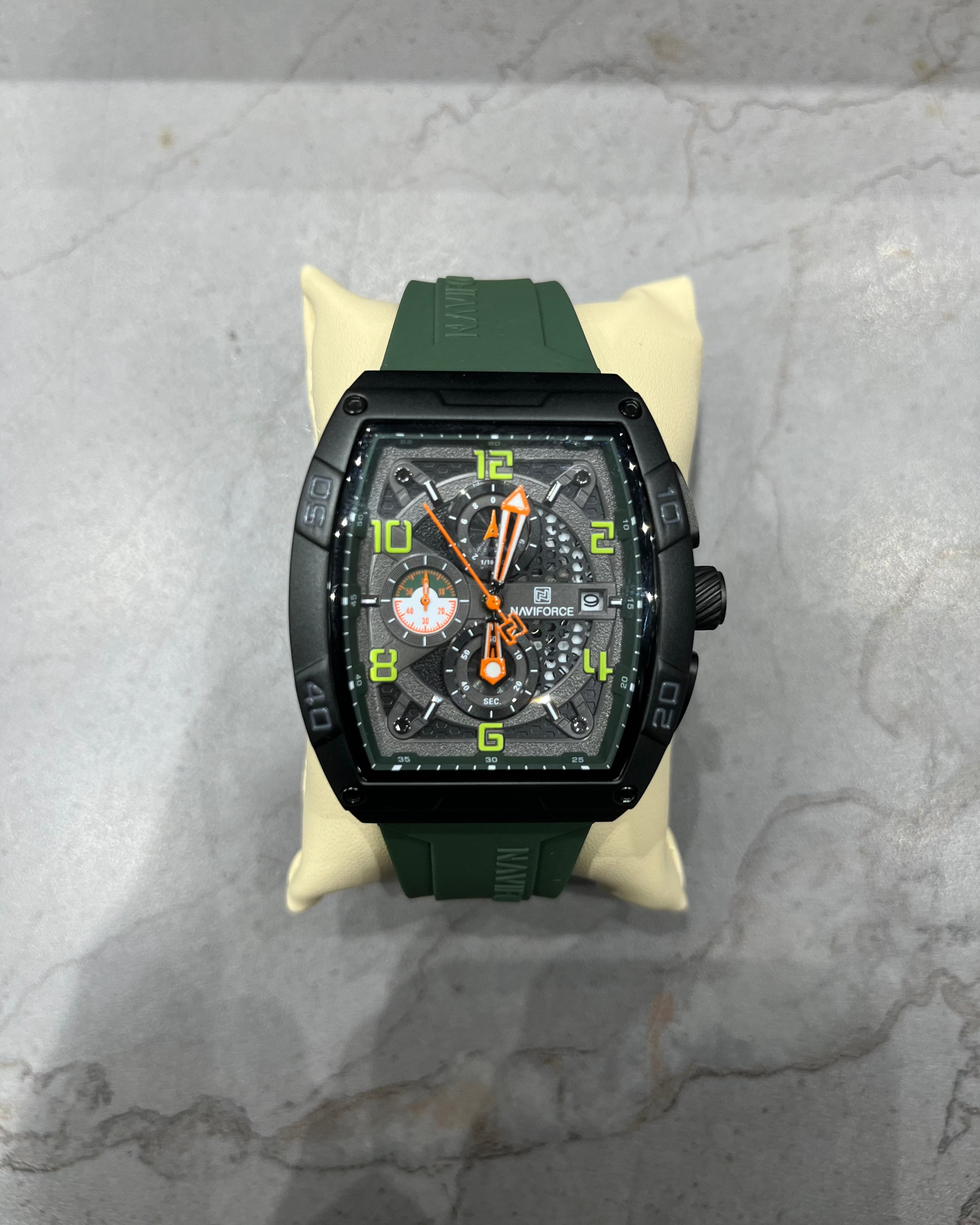 Luxury watch with green strap and black case on a marble surface