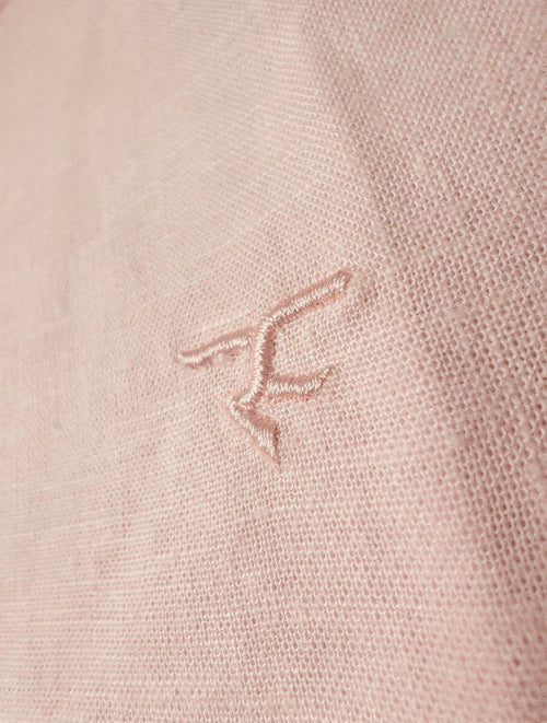 Close-up of a pink textured fabric with a logo or brand emblem.