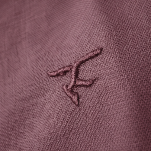 Close-up of a embroidered logo on a textured plum fabric
