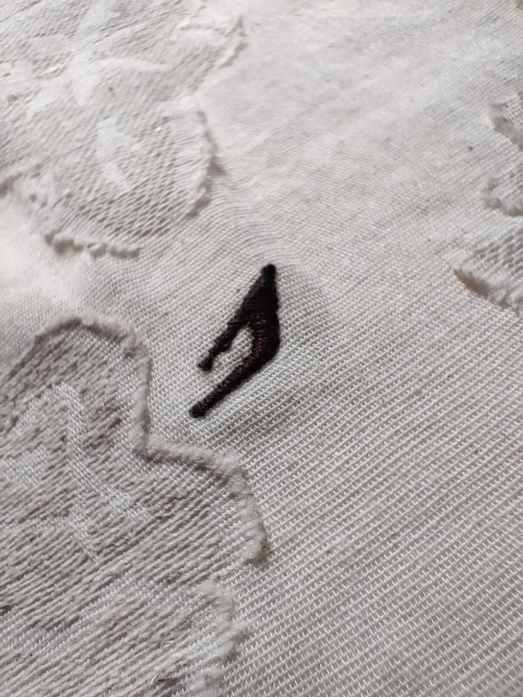 Close-up of a textured gray fabric with a black logo on a white background