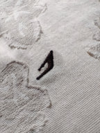 Close-up of a textured gray fabric with a black logo on a white background