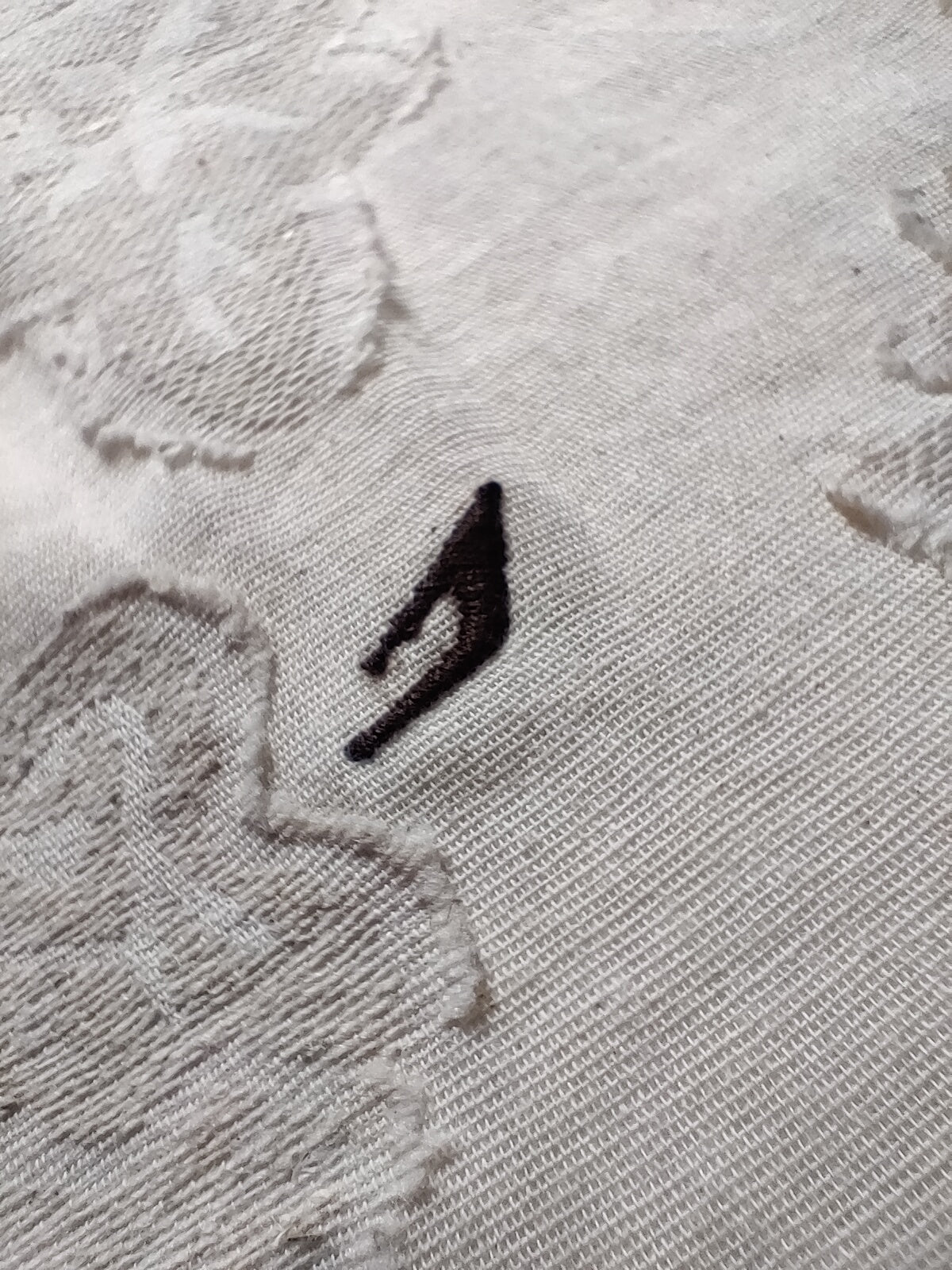 Close-up of a textured gray fabric with a black logo on a white background