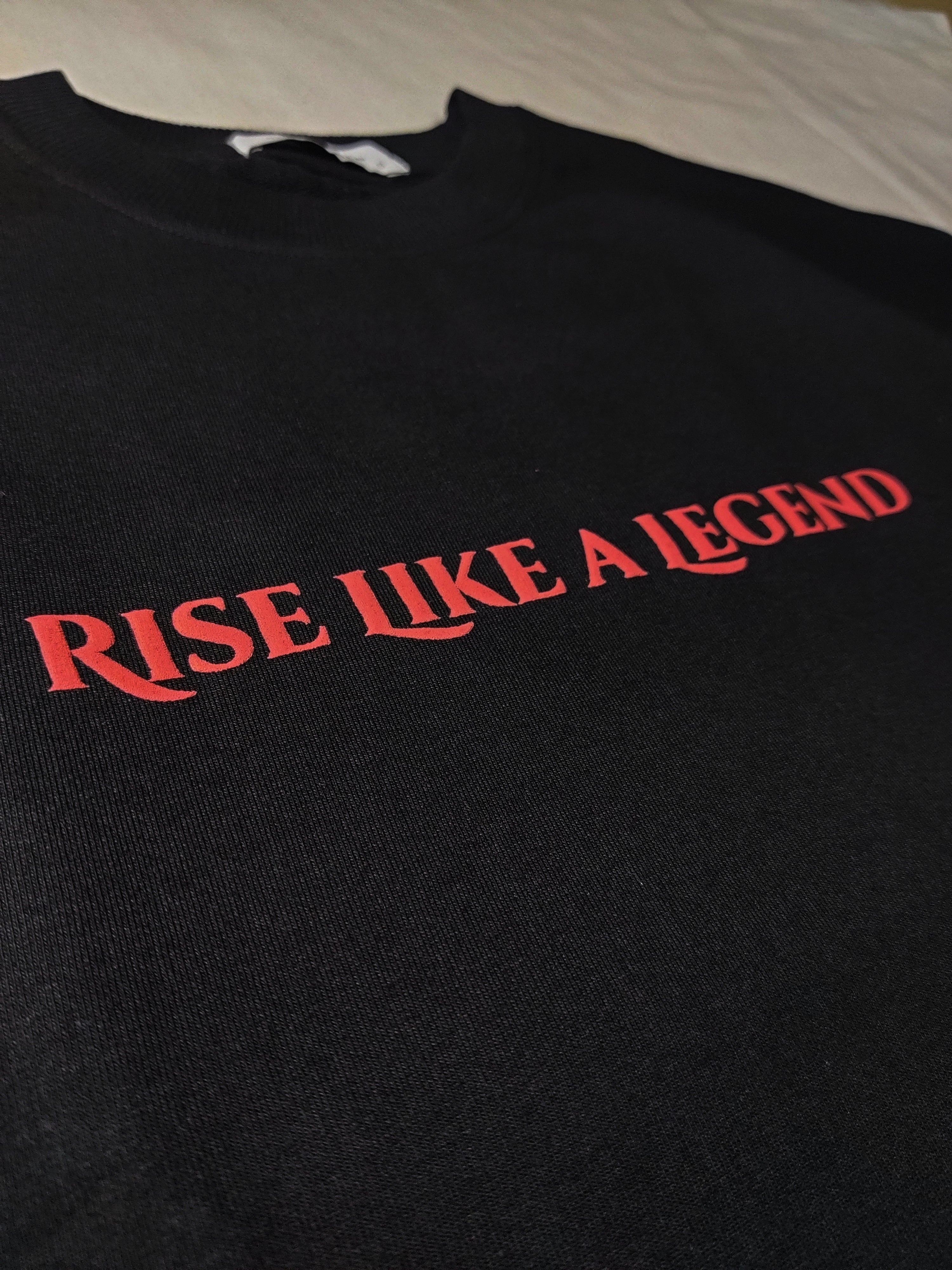 Black sweatshirt with 'Rise Like a Legend' text in red on a plain background