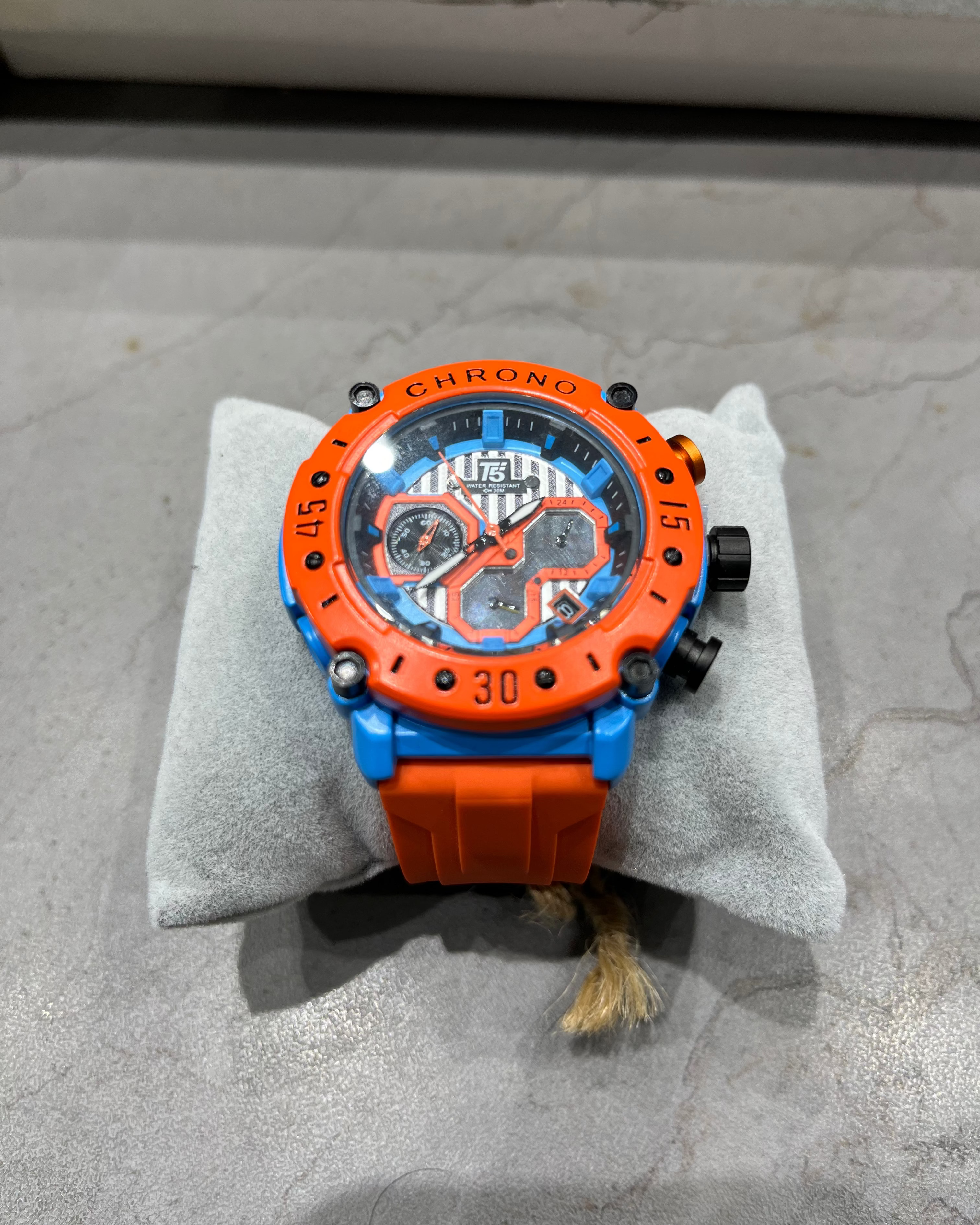orange blue watch on a grey cushion on a grey table