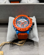 Orange and blue watch on a gray cushion with a blurred background