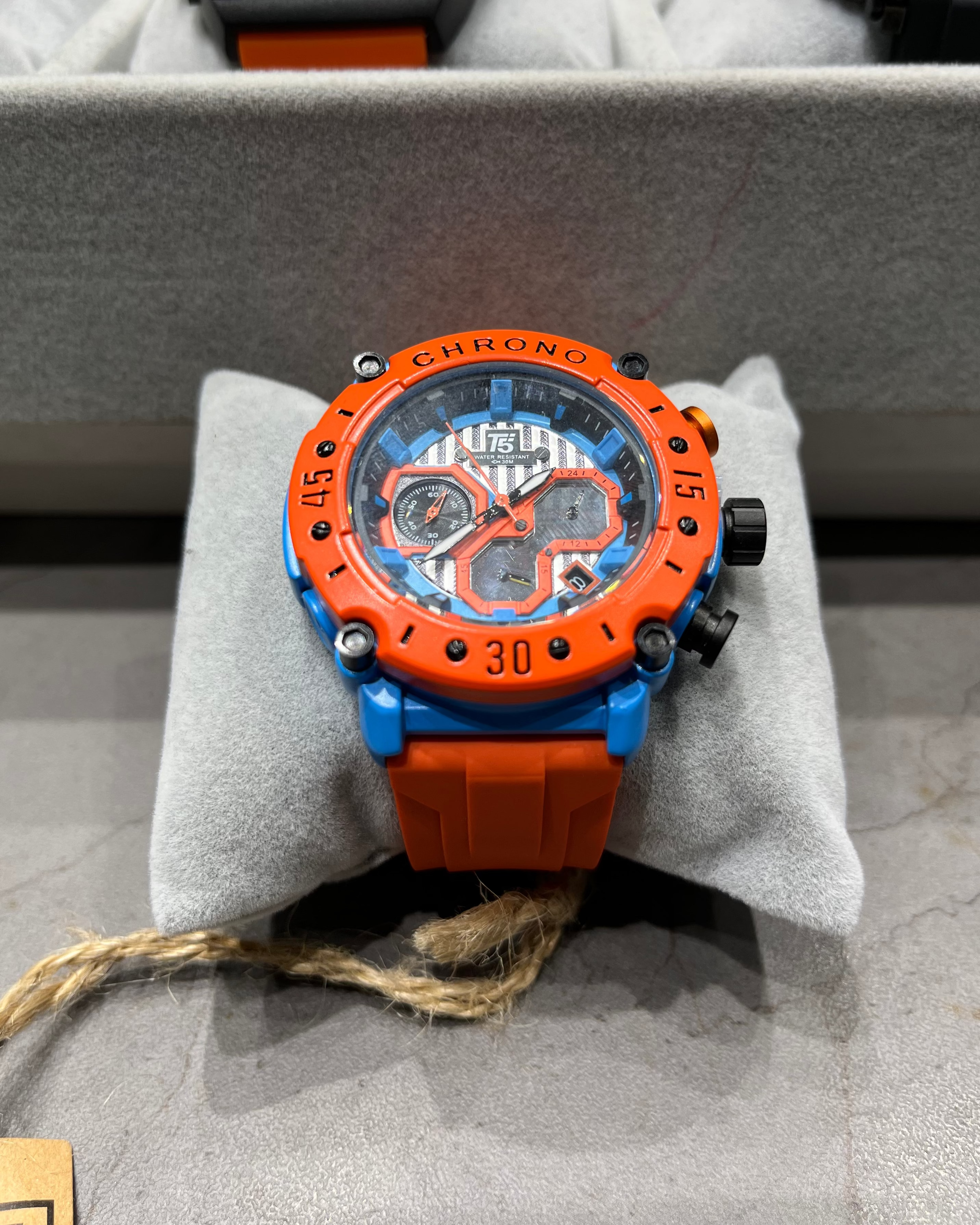 Orange and blue watch on a gray cushion with a blurred background