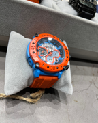 Orange and blue watch on a gray surface with blurred background