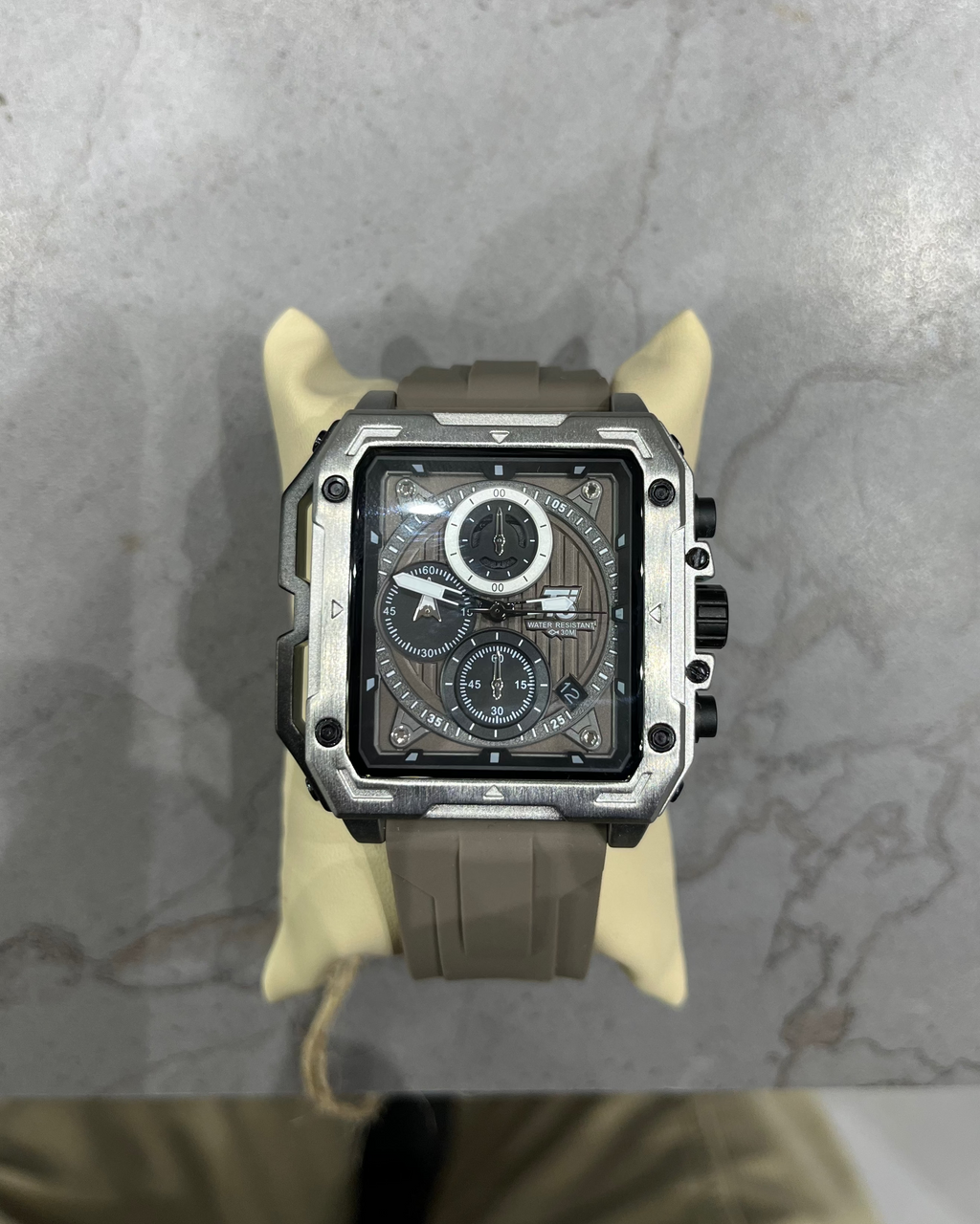 Watch with a brown strap on a marble surface