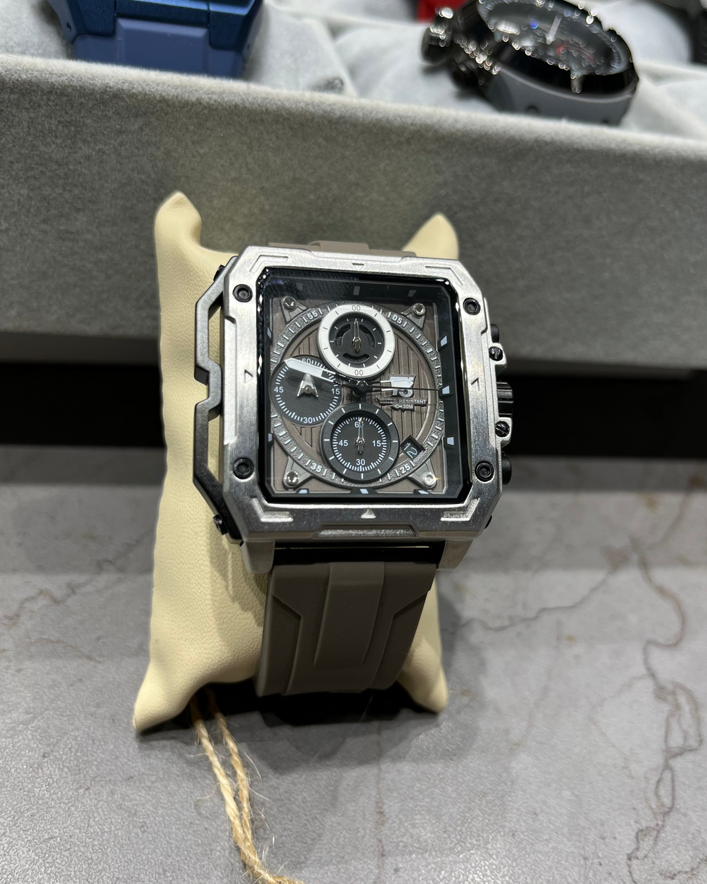 Luxury watch with a detailed face on a gray surface, surrounded by other watches.