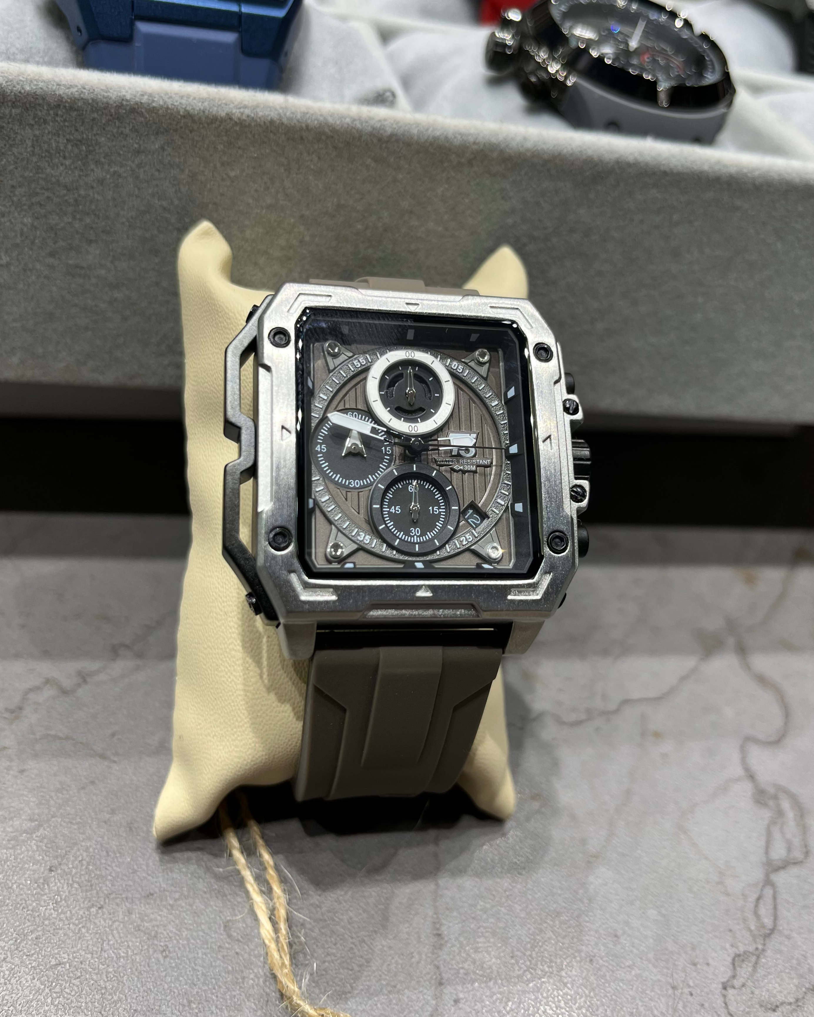 Luxury watch with a detailed face on a gray surface, surrounded by other watches.