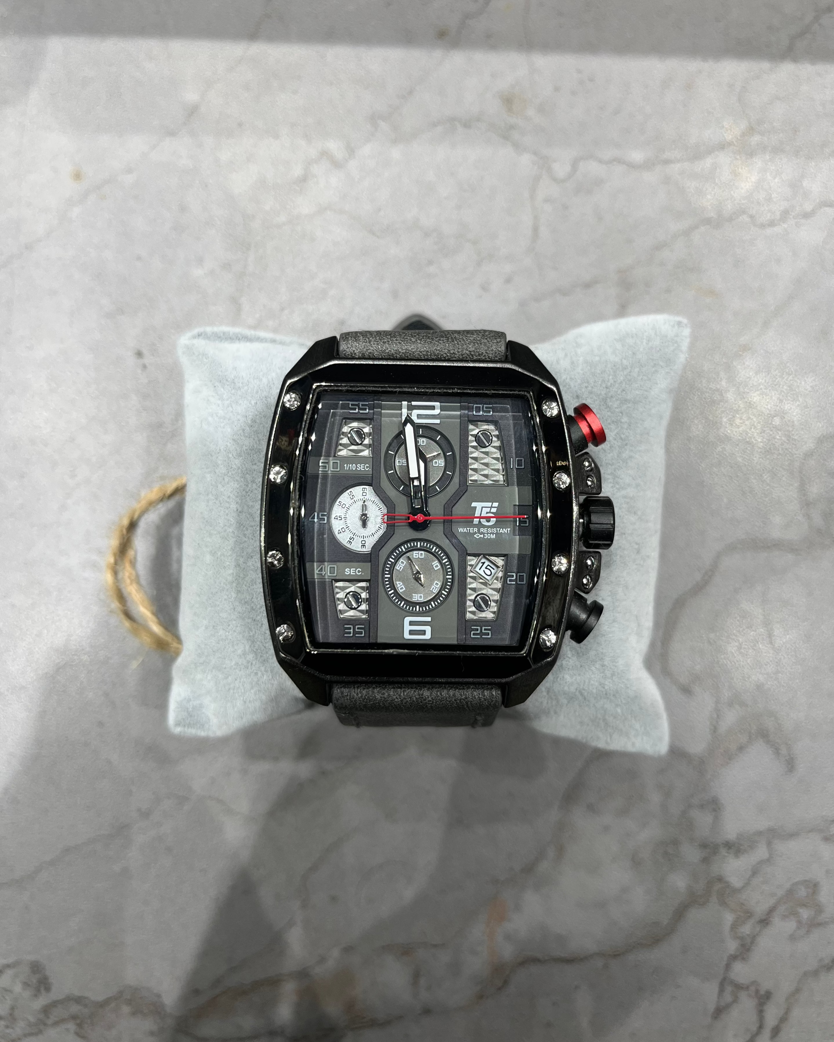 Black wristwatch with multiple dials on a gray marble surface