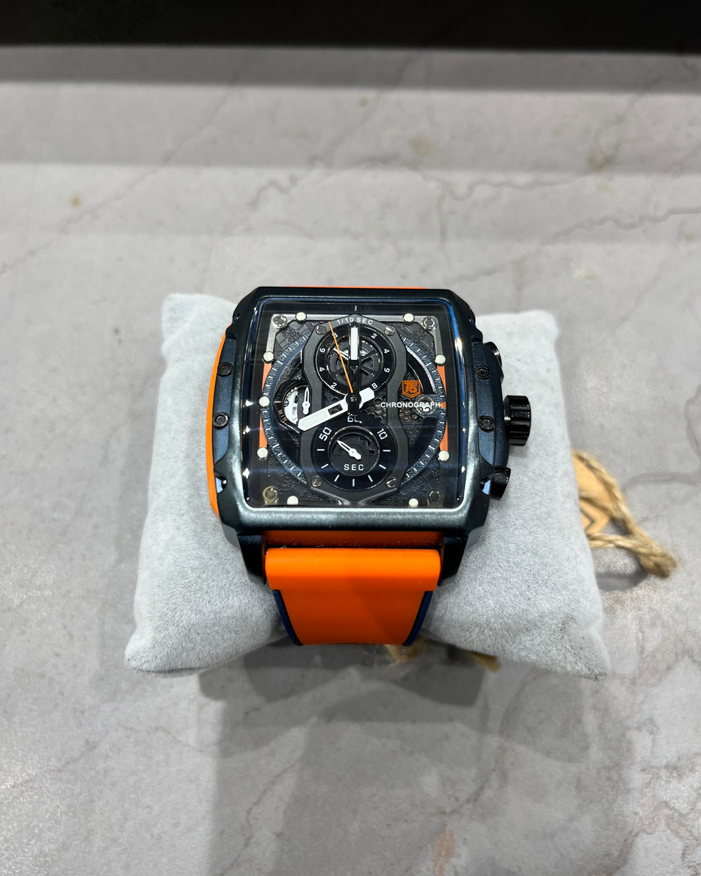 Watch with orange strap on a gray surface