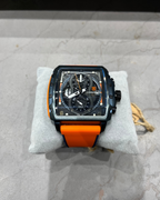 Watch with orange strap on a gray surface
