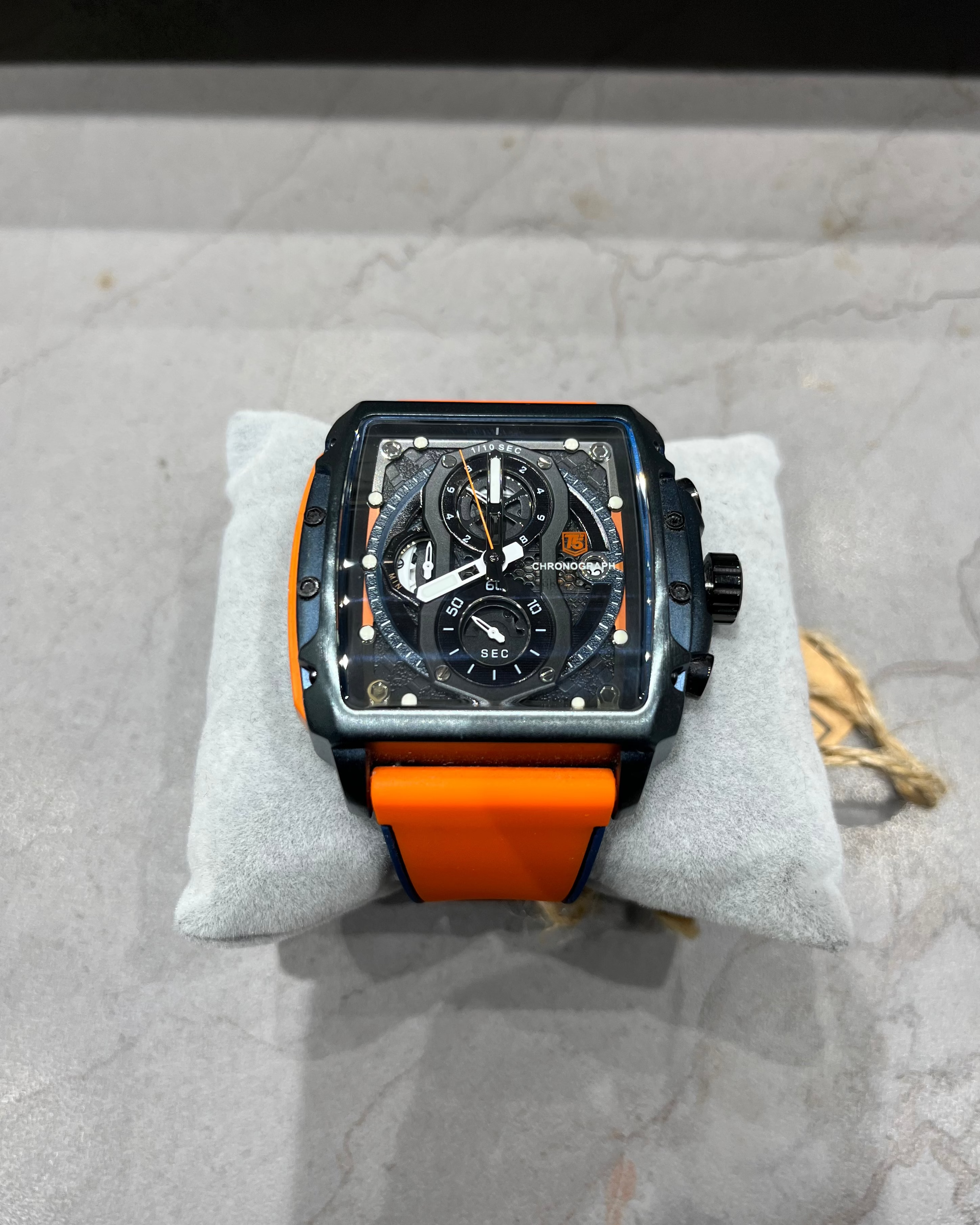 Watch with orange strap on a gray surface