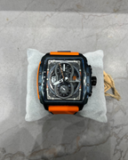 Luxury watch with orange accents on a gray marble surface