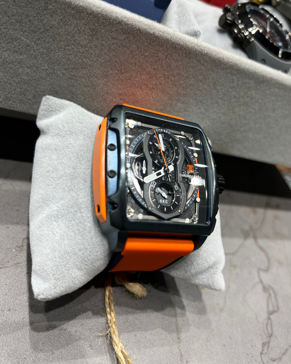 Watch with orange and black casing on a gray surface