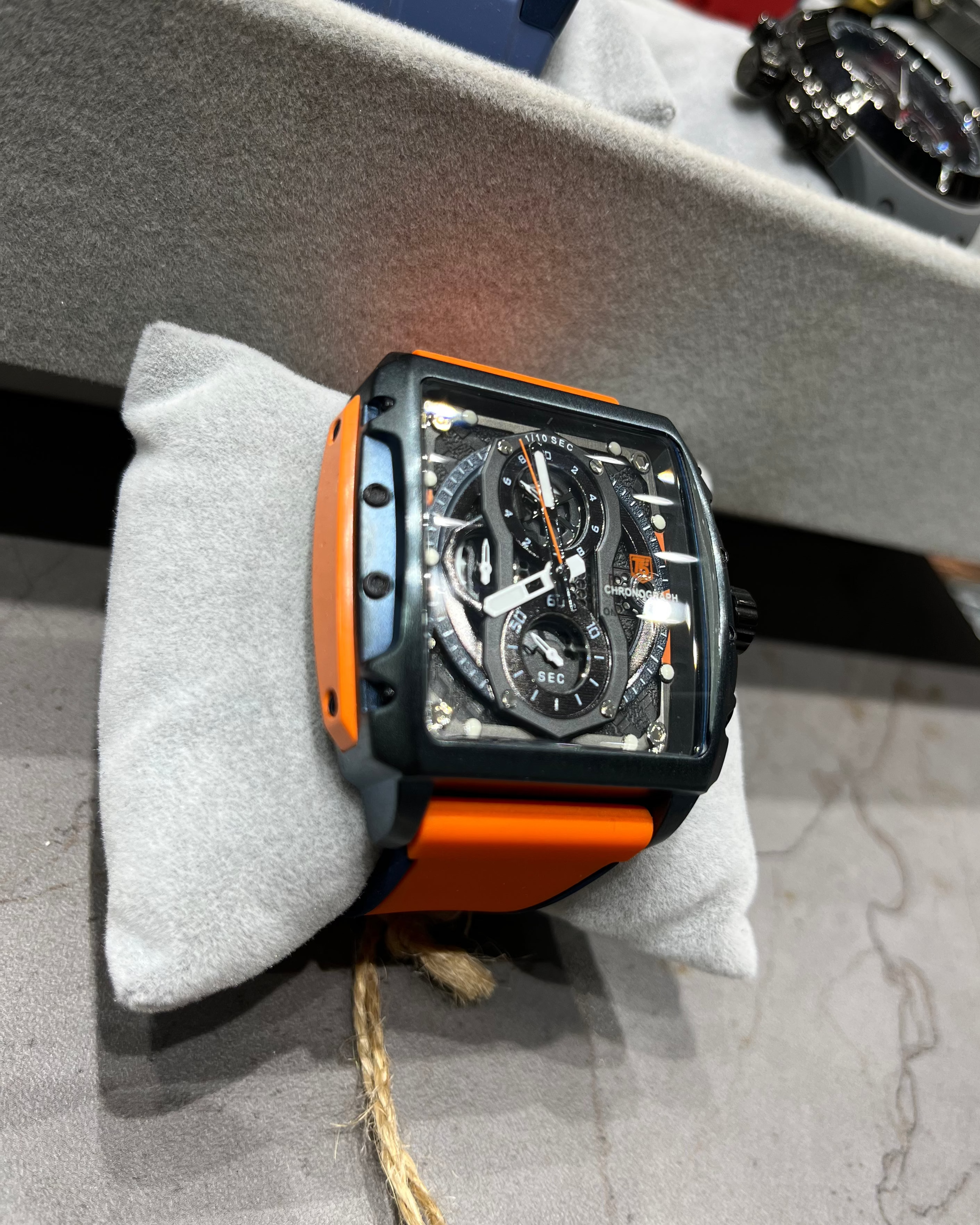 Watch with orange and black casing on a gray surface