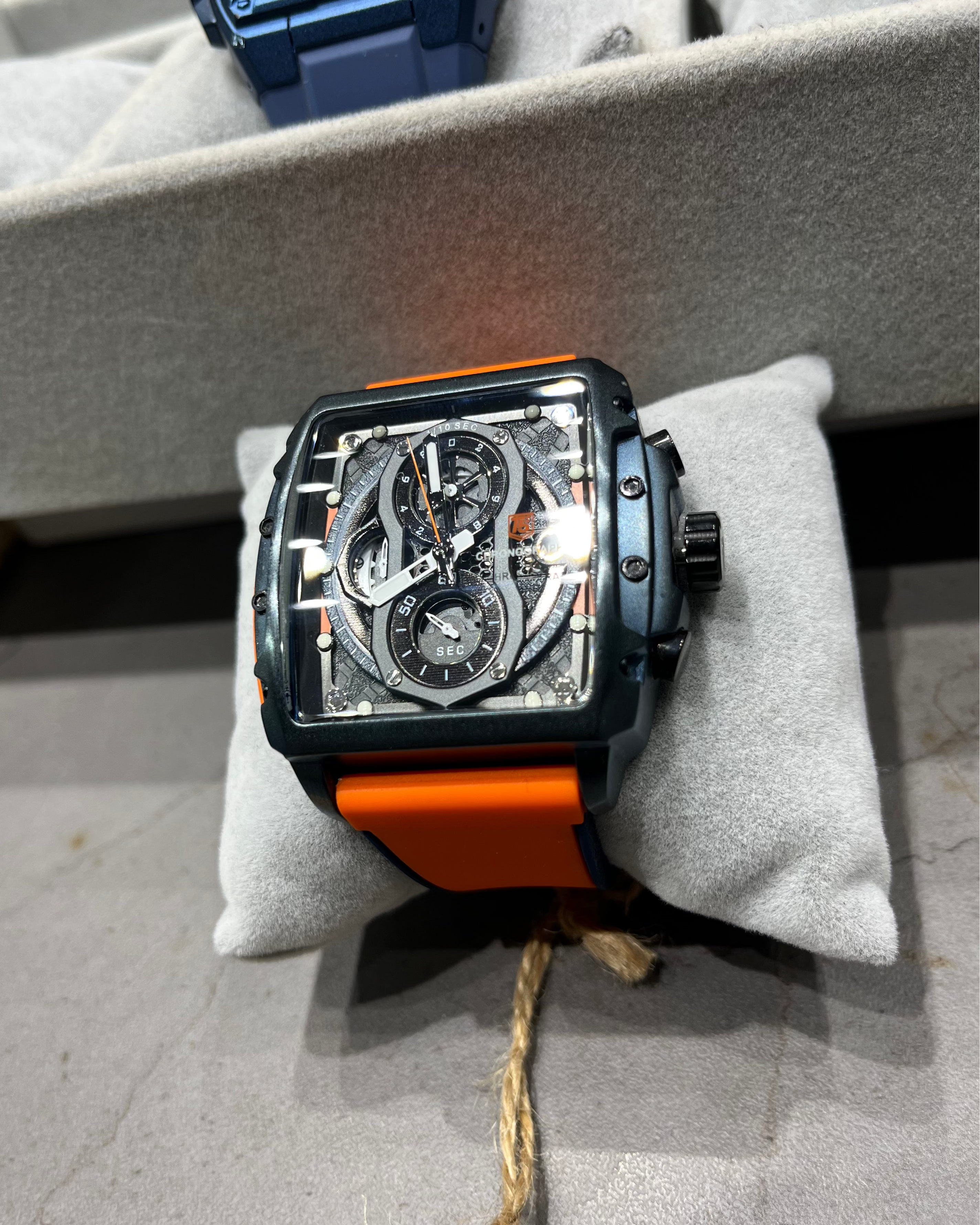 Watch with orange strap on a gray surface