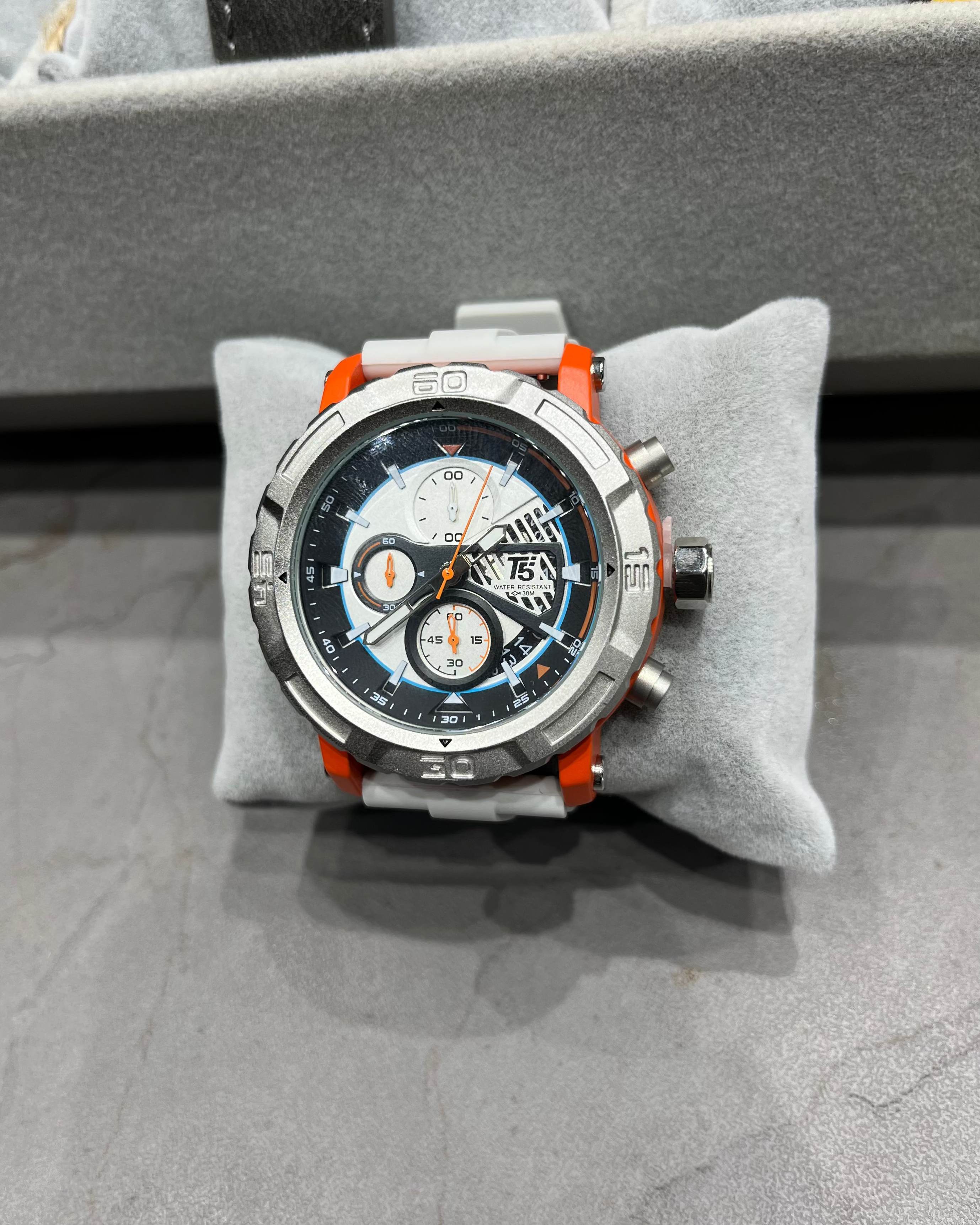 Chronograph watch with orange accents on a gray cushion