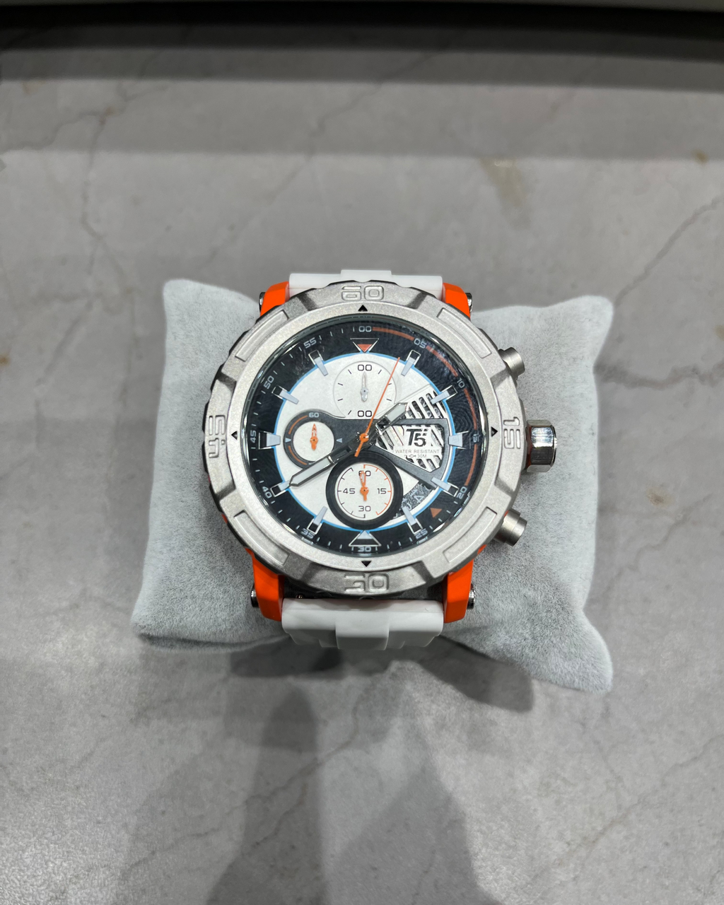 Luxury watch with a detailed face on a gray cushion against a marble background
