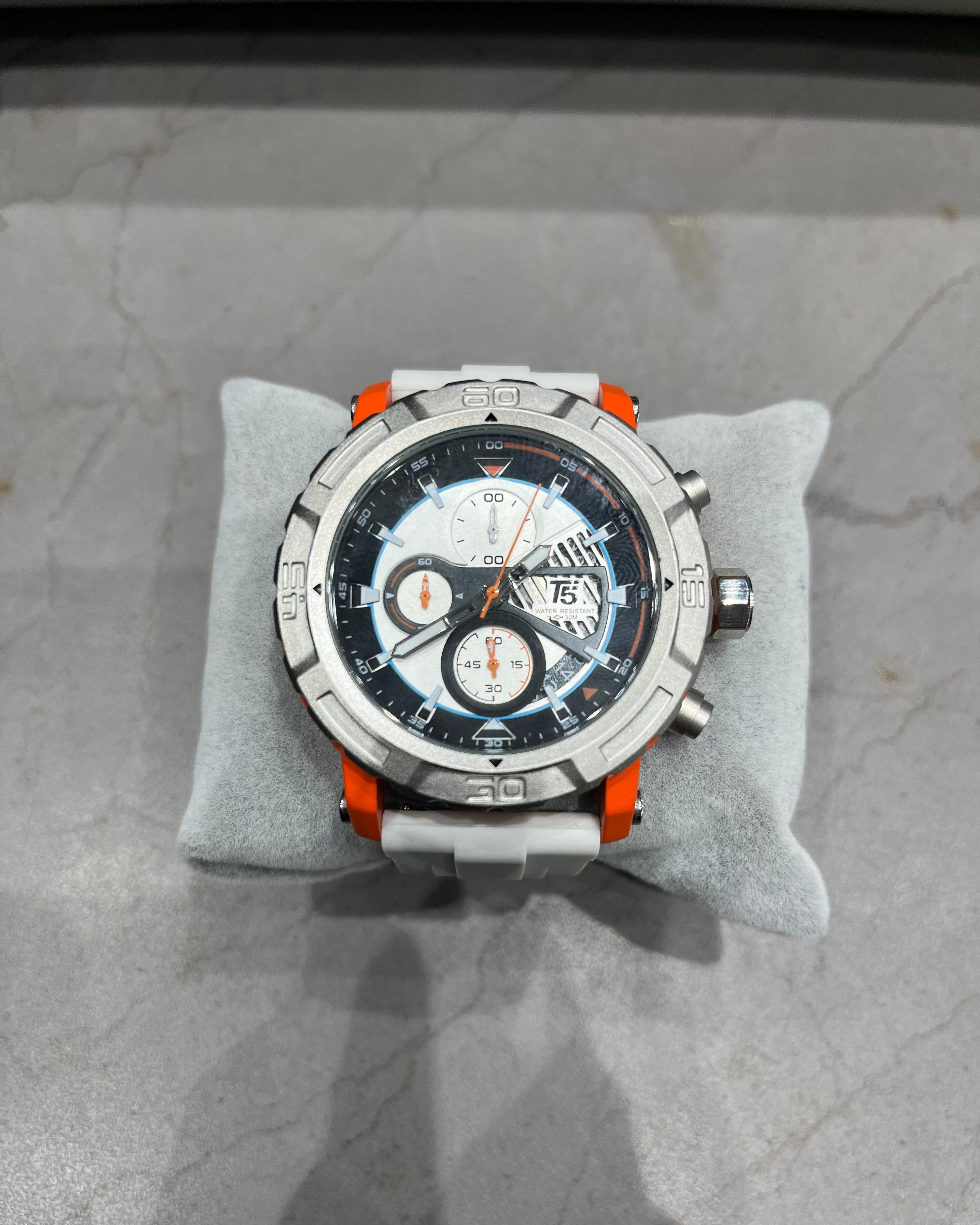 Luxury watch with a detailed face on a gray cushion against a marble background